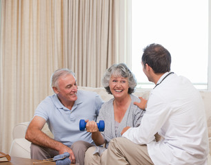 Obraz premium Handsome doctor helping his patient to do exercises