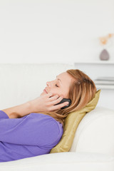 Profile portrait of a serene red-haired woman on phone while lyi