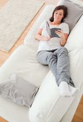 Young good looking female reading a book while lying on a sofa