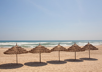 Blue sky as a background and row of straw umbrellas.