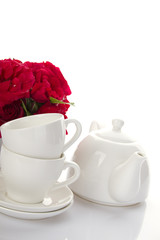 White crockery for tea and a bouquet of roses