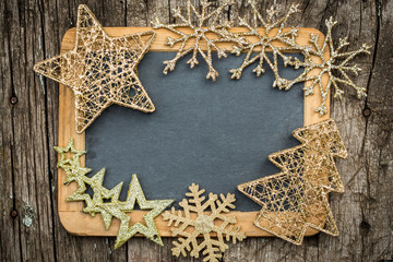 Gold Christmas tree decorations on vintage wooden blackboard