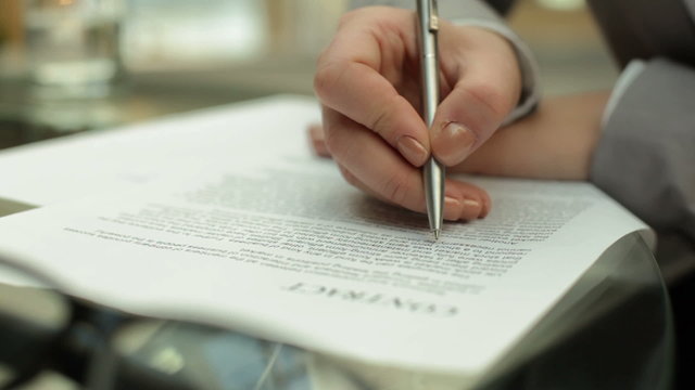 Hand of businesswoman writing on paper at workplace