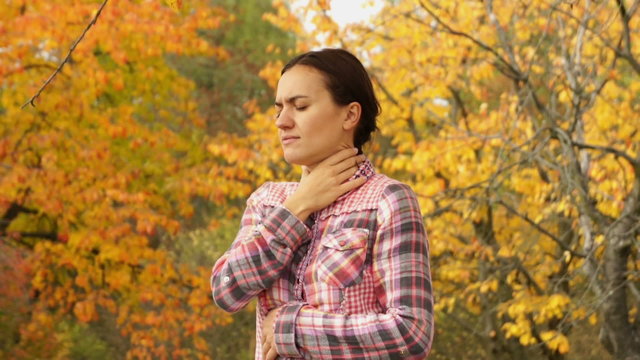 Sick woman coughing in autumn park