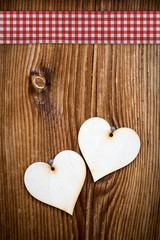 two wooden hearts on dark wooden planks with checked ribbon