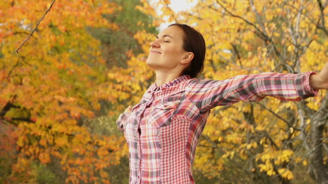 Excited woman standing in a park with hands outstretched