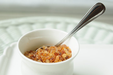 White cup of brown sugar on rattan table.