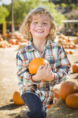 Fototapeta premium Little Boy Holding His Pumpkin at a Pumpkin Patch.