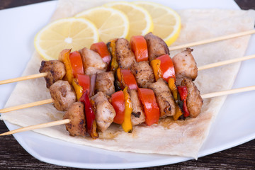 Tasty grilled meat and vegetables on skewer on plate