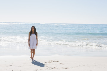 Fototapeta na wymiar Brunetka w białej sukni spaceru do morza słońca