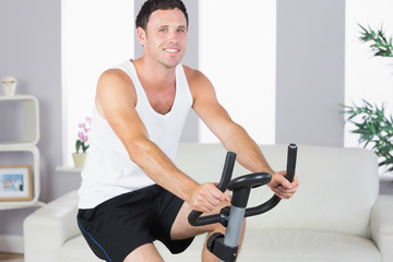 Obraz na płótnie Canvas Cheerful sporty man exercising on bike
