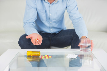 Casual man showing pills on open hand