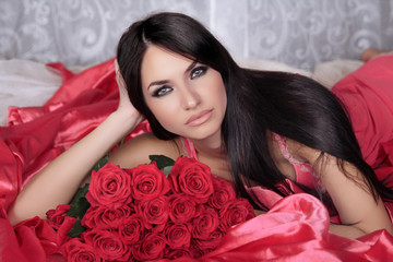Obraz na płótnie Canvas Beauty portrait. Amazing brunette woman with Red Roses lying on