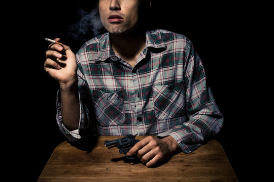 Atmospheric shot of man with gun smoking cigarette