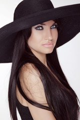 Fashion brunette woman model posing in black hat isolated on whi