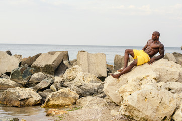 Black bodybuilder relaxing on the beach after a hard workout