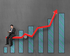 Businessman using tablet and sitting on growth red arrow with ch
