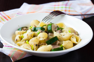 Pasta with tuna, zucchini, sauce and herbs on plate, delicious