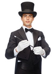 magician in top hat with magic wand showing trick