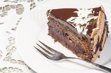 Slice of chocolate cake decorated with white chocolate flakes