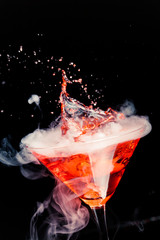 red cocktail with splash and ice vapor