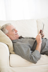 Senior Man Using Digital Tablet At Home