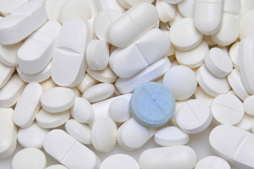 Fototapeta na wymiar blue tablet among white pills background