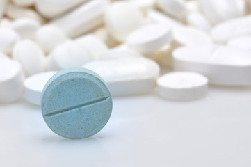 blue tablet among white pills background