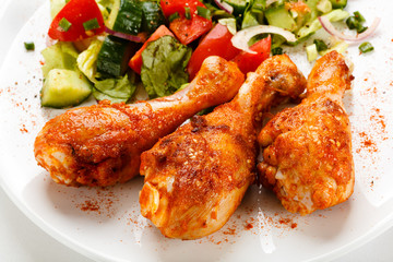 Grilled chicken legs and vegetables on white background