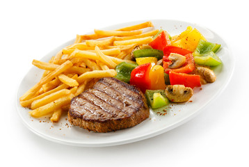 Grilled steaks, French fries and vegetables