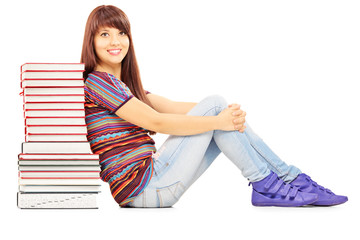 Confident female student leaning on a pile of books