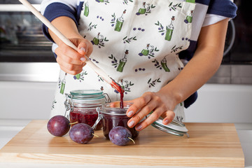 Housewife filling the jar with jam