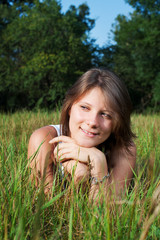 Beautiful teenage girl lying on the green grass