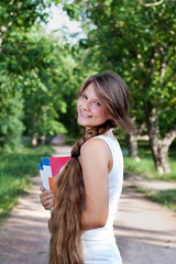 Beautiful teenage girl with long braid in the park
