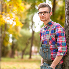 hipster standing in autumn park grin