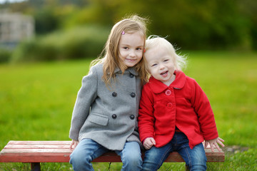 Fototapeta na wymiar Two little sisters hugging on a bench