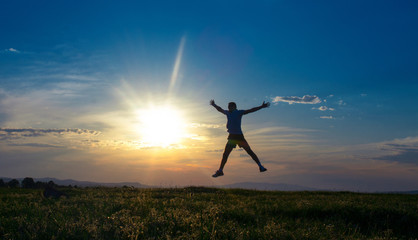 Silhouette man jumping with open arms on sundown - sunrise