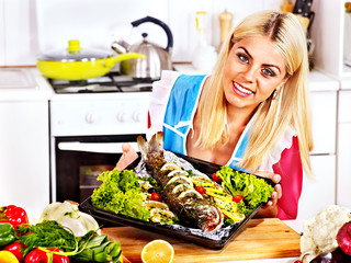 Woman prepare fish in oven.