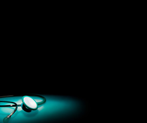 Stethoscope in a spotlight on blue reflective table