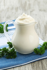 Sour cream in pitcher on table close-up