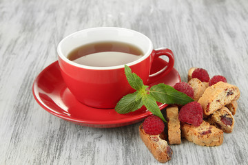 Cup of tea with cookies and raspberries on table close-up