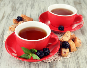 Cups of tea with cookies and blackberry on table close-up