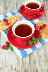 Cups of tea with cookies and raspberries on table close-up