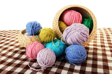 Multicolored clews in wicker basket with plaid closeup