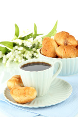 Tasty croissants and cup of coffee on table on white background