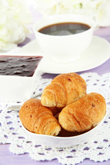 Tasty croissants and cup of coffee on table close-up