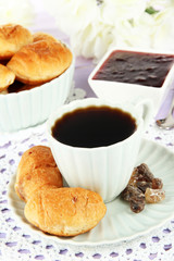 Tasty croissants and cup of coffee on table close-up