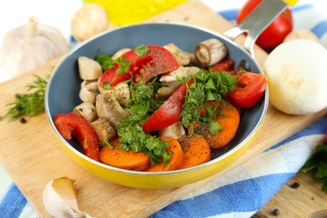 Sliced fresh vegetables in pan on wooden board isolated on