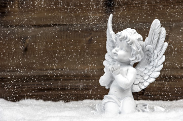 little white angel on wooden background in snow