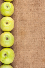 Green apples lie on sackcloth